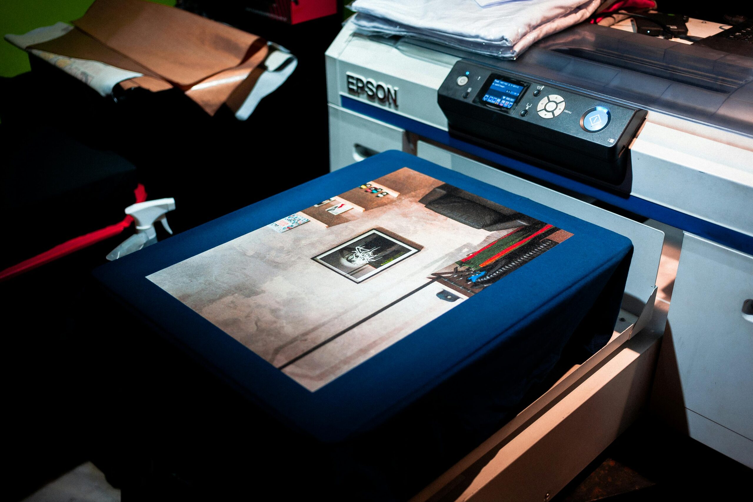 Close-up of a professional printer printing a custom artwork design on fabric in a studio setting.